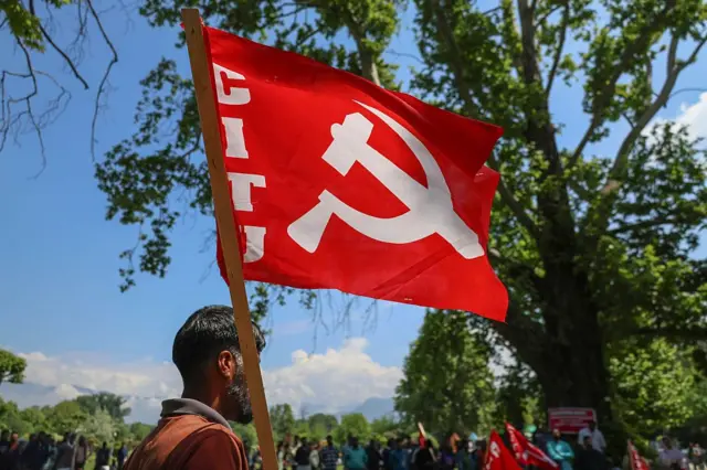 Un trabajador subcontratado sostiene la bandera del Partido Comunista de la India (Marxista) (CPI-M) durante una manifestación