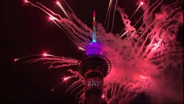 オークランド中心部のタワーの後ろに、花火の赤い光と煙が見える