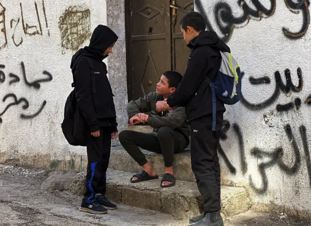 Karim sitting on steps and talking to two male friends