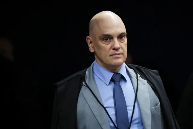 Moraes com olhar sério, de toga, em pé