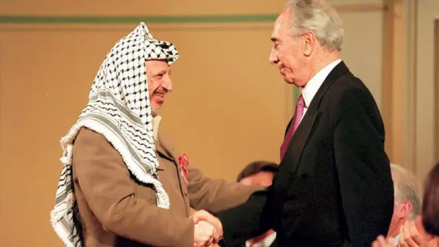 former Israeli Foreign Minister Shimon Peres and former Palestine Liberation Organization chairmo Yasser Arafat dey shake hands