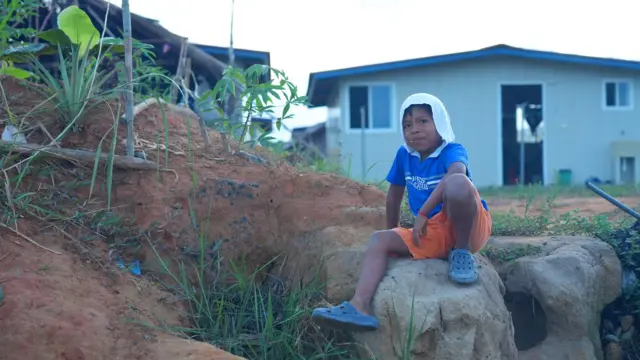 Um menino posa em um espaço atrás de sua casa na favela de Isberyala.