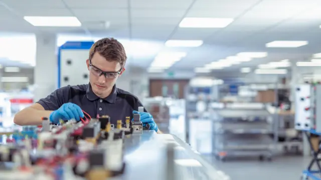 Engenheiro aprendiz trabalhando em maquinário de fábrica.