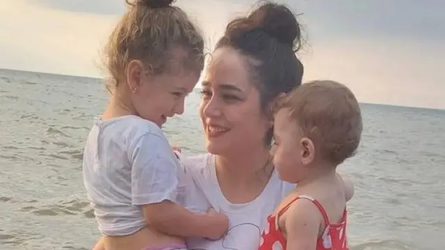 Nazanin hugging her two daughters, Deniz and Delsa beside the sea