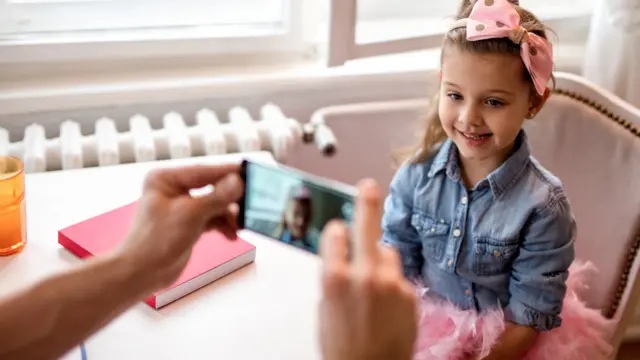 Niña siendo fotografiada con un celular
