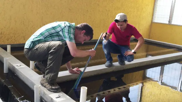 Ingeniero Monroe Weber-Shirk trabaja en una planta junto a un joven integrante de la comunidad