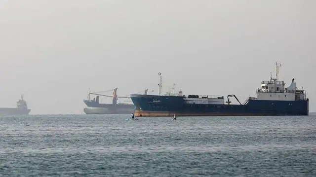 海上に数隻の大型船と、2隻の1人乗りのボートが見える