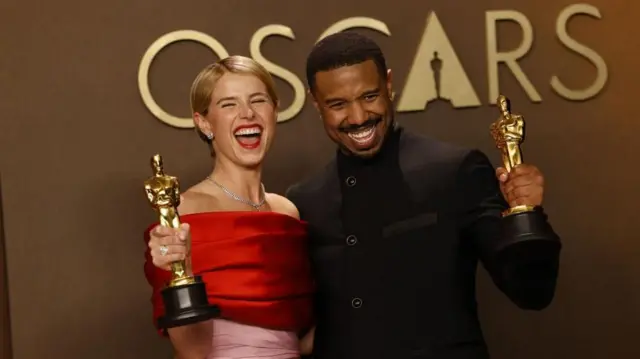 「OSCARS」と書かれた背景を前に、それぞれオスカー像を手にして大きい笑顔を浮かべるバックリーさんとジョーダンさんが寄り添っている。バックリーさんは赤とピンクのドレス、ジョーダンさんは黒いスーツを着ている