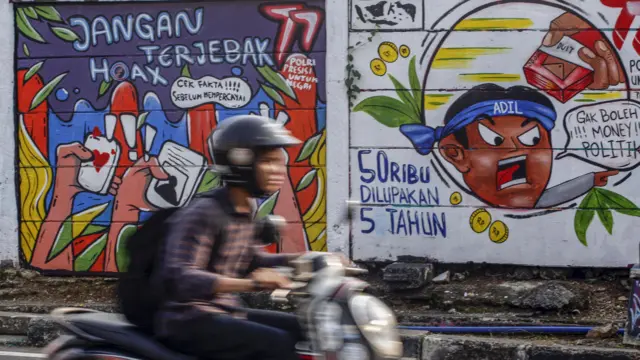 Warga melintas di depan mural yang berisikan tolak politik uang jelang Pemilu tahun 20, di Depok, Jawa Barat, Jumat (28/07).