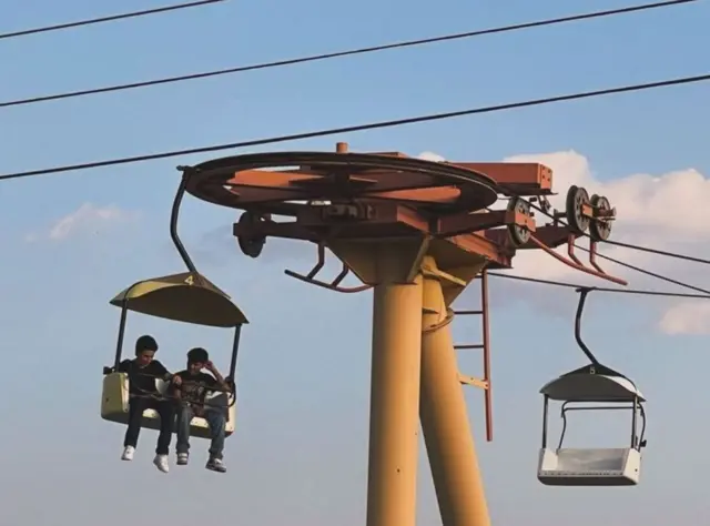 Dos niños en un tiovivo del parque de atracciones de Sunland Park, Nuevo México, el 25 de julio de 2024.