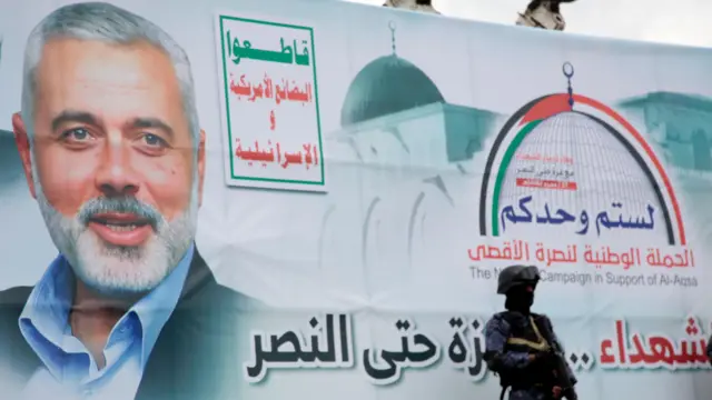 One soja stand next to one banner wey get foto of Hamas political leader Ismail Haniyeh
