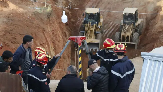 Rescuers stand near diggers