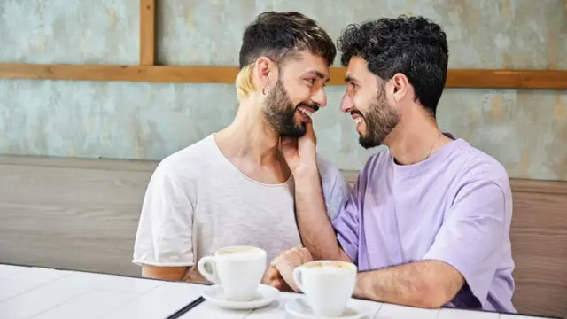 Pareja gay viviendo un momento íntimo mientras toman café.