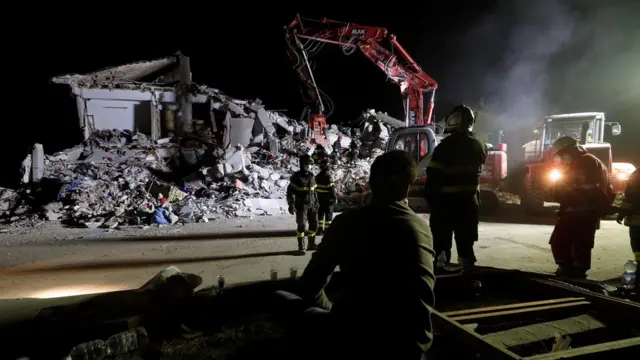 Firefighters work in the night at a collapsed house following an earthquake in Amatrice