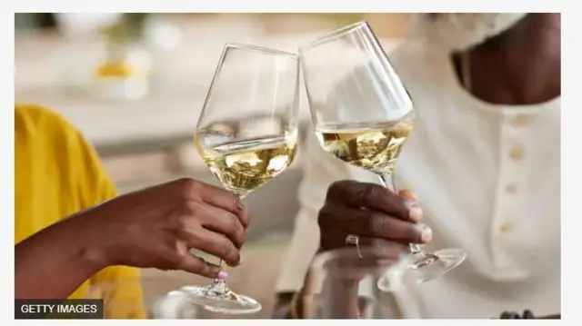 Aworan ọwọ meji to n fi ife ọti kan ara wọn pẹlu ọti ninu rẹ