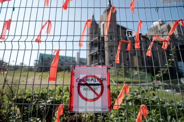 Un cartel que dice "El colonialismo está prohibido" y trozos de tela de color naranja cuelgan en el sitio del antiguo Hospital Royal Victoria antes de la manifestación y marcha "Every Child Matters" el 30 de septiembre de 2023 en Montreal, Canadá. La marcha tenía como objetivo llamar la atención sobre las atrocidades que ocurrieron durante la época del sistema de escuelas residenciales. (Photo by ANDREJ IVANOV/AFP via Getty Images)