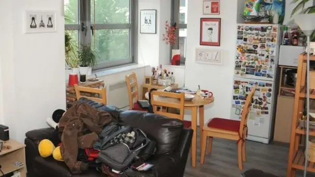 Foto apartemen Reynhard Sinaga di Manchester. Terdpat sofa kulit warna gelap, beberapa kursi, meja makan, dan kulkas yang dipenuhi tempelan magnet.