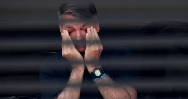 Imagem mostra Bolsonaro atrás das grandes de sua casa. Ele coloca as mãos nos olhos em pose que parece demonstrar cansaço