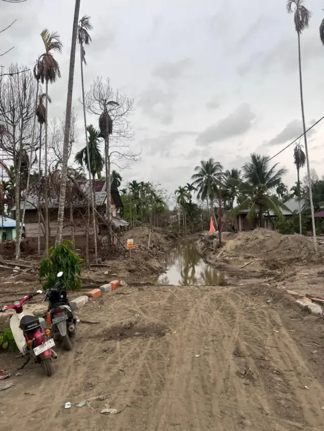 Kondisi jalan di permukiman warga di Meureudu, Pidie Jaya, pada Rabu (18/02) yang penuh lumpur. 