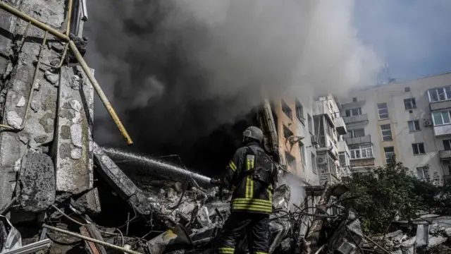 ডনবাসে রুশ গোলার আঘাতে বিধ্বস্ত এক বাড়িতে আগুন সামাল দেয়ার চেষ্টা করছেন একজন দমকল কর্মী।