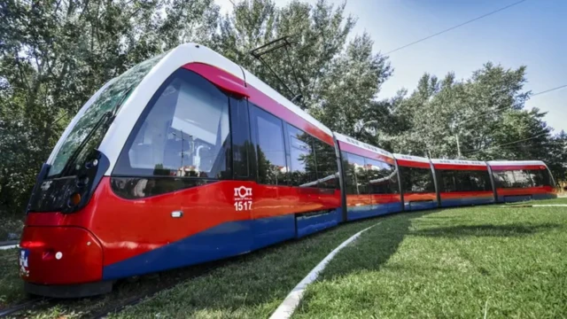 Савремени трамвај у бојама државне заставе Србије окружен зеленилом