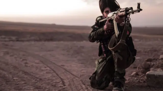 Garota peshmerga mirando com fuzil AK 47