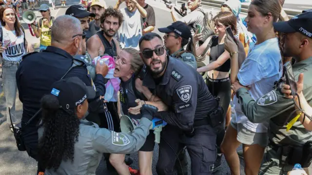 شرطي إسرائيلي يشتبك مع متظاهرة في تل أبيب.