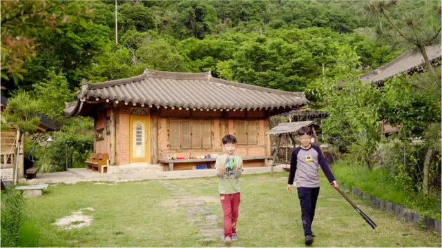 Sihu and his little brother play baseball in front of their house