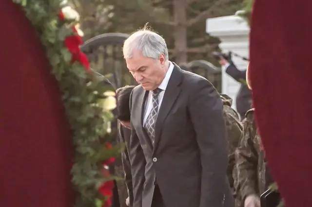 Володин на церемонии сфотографирован между двумя венками. Он наклонил голову.