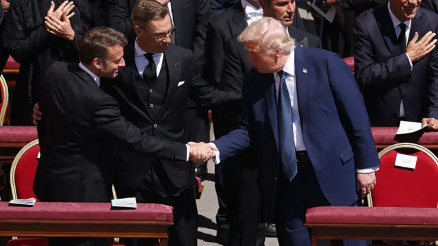 Макрон пожимает руку Трампу.