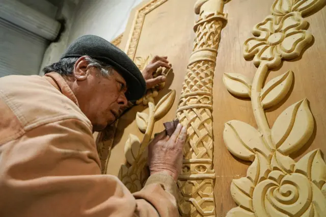 A man carves into a wooden door with great care.