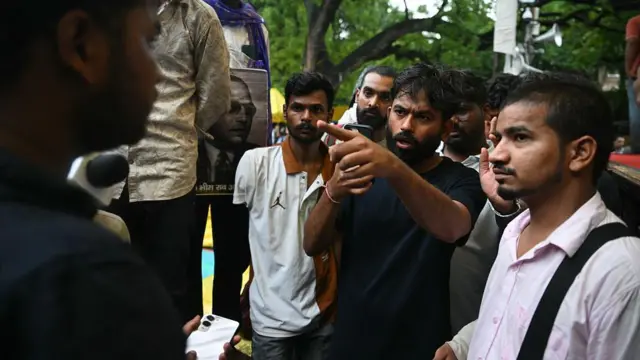अभिजीत दीपके कई लोगों के साथ हाथ से इशारा करते हुए