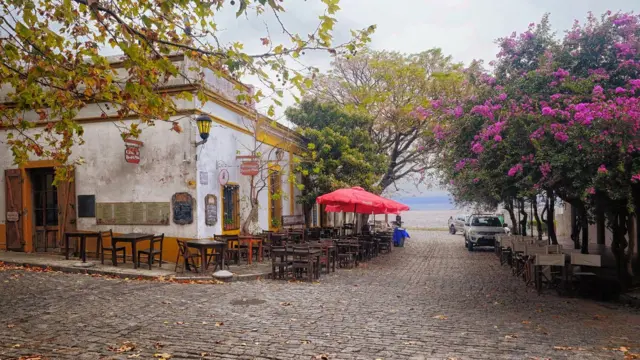 O centro histórico de Colonia del Sacramento, no Uruguai, com ruas de paralelepípedos, mesas nas calçadas e primaveras em flor