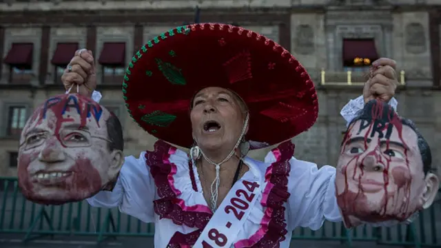 Una mujer sostiene máscaras de Calderón y Peña Nieto