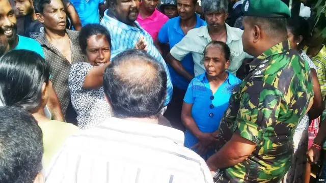 බලධාරීන් සමග තත්වය විස්තර කරන ගම්වාසීන්