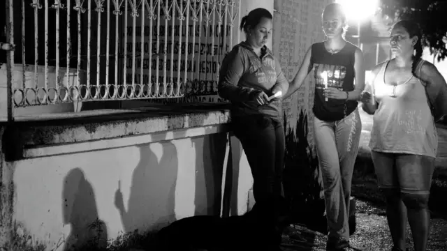 Mujeres con velas frente al cementerio.