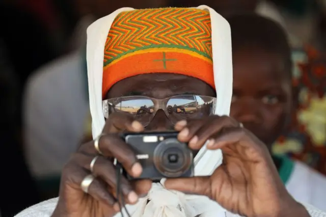 A man takes a picture during the inauguration ceremony of the solar energy power plant in Zaktubi, near Ouagadougou, on november 29, 2017, on the second day of France's President Emmanuel Macron first African tour since taking office.
