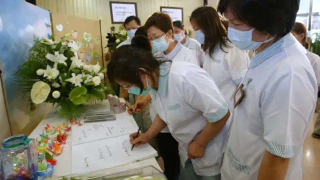 সার্স রোগে আক্রান্ত একজনের জন্য খোলা শোকবইয়ে স্বাক্ষর করছেন স্বাস্থ্যকর্মীরা