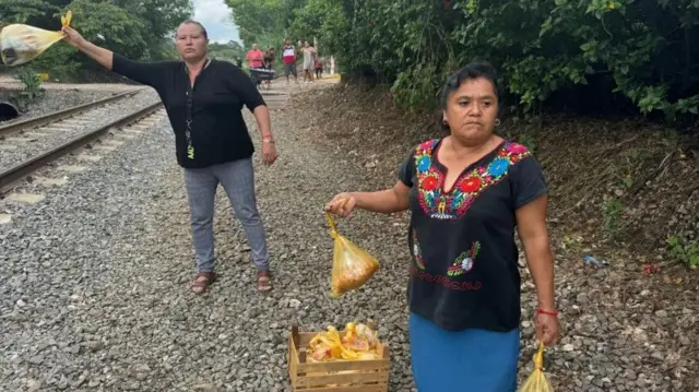 Las Patronas tendent des sacs de nourriture à l'approche d'un train.