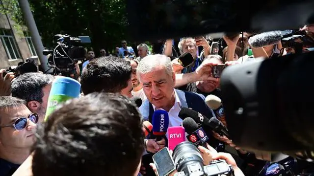 Самвел Карпетян прийшов на виборчу дільницю, перебуваючи під домашнім арештом через звинувачення у спробах захоплення влади . Він стоїть в оточенні журналістів з мікрофонами.