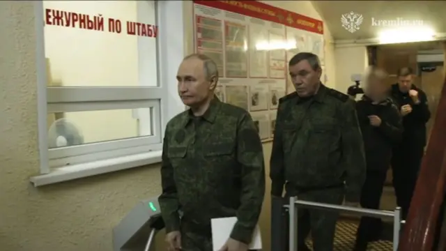 Üniformalı Rusya lideri Vladimir Putin, arkasındaki yetkililerle yürürken.