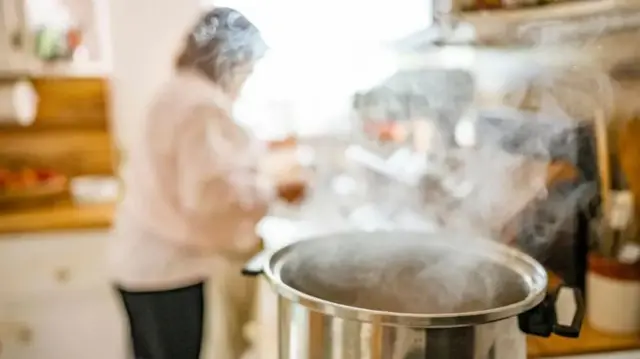 یک قابلمه روی اجاق گاز که بخار از آن بیرون می آید