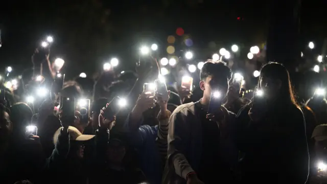 A group of spectators shining lights from their mobile phones during a tribute to the victims of the Bondi terror attack during the New Year's Eve Celebrations at Mrs Macquaries Point in Sydney, Australia