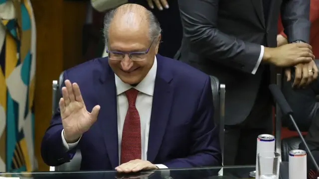 Alckmin sorrindo e acenando, sentado no Congresso