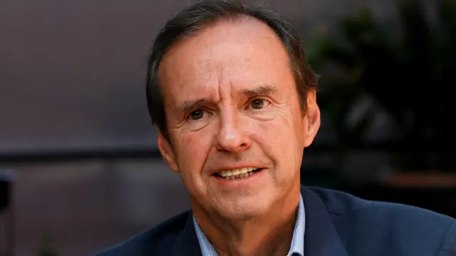 Primer plano de Jorge Tuto Quiroga, con media sonrisa y vestido de azul.
