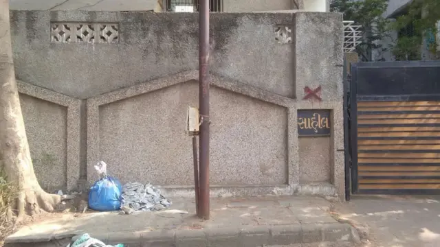 સાહિલ સોસાયટીના દરવાજા પરની લાલ ચોકડીનો ફોટોગ્રાફ