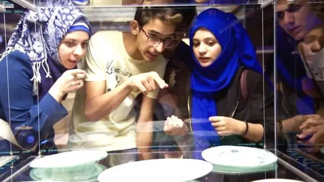 મ્યૂઝિયમની અંદર વસ્તુઓ જોતા લોકો