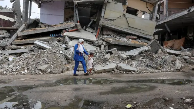 A displaced Palestinian mother, Wafaa Abdelhadi, walks past the rubble of a house destroyed in an Israeli strike as she returns to her shelter with her daughters Lynn and Roueida, after they got vaccinated against polio, in Deir Al-Balah, in the central Gaza Strip September 1, 2024. REUTERS/Ramadan Abed TPX IMAGES OF THE DAY