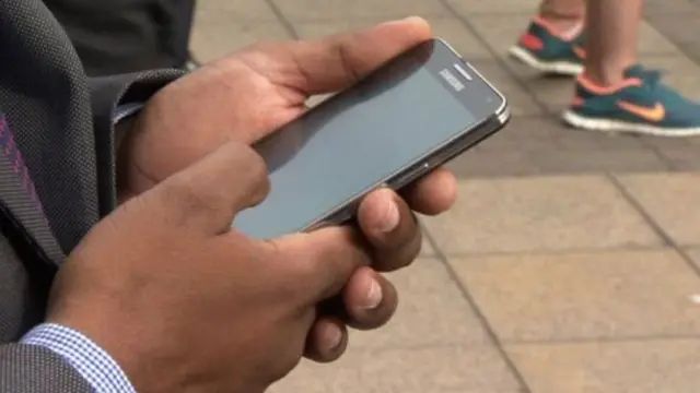 હાથમાં મોબાઈલ ફોન રાખીને મોબાઈલ ફોનની સ્ક્રીન તરફ જોઈ રહેલા મોબાઈલ ફોન ધારકની પ્રતિકાત્મક તસ્વીર