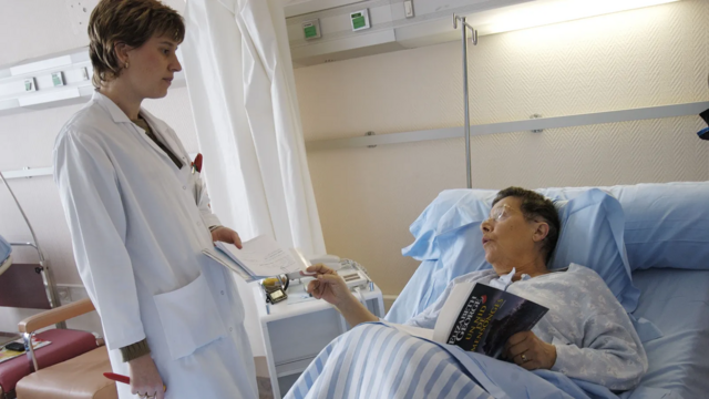 Paciente idosa conversa com médica em leito de hospital